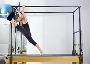 Category Oldtimer Prints: Pilates woman in cadillac split legs stretch exercise at gym