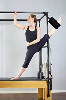 Pilates woman in cadillac split legs stretch exercise at gym