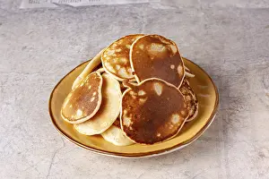 A pile of pancakes lies in a yellow clay plate close-up