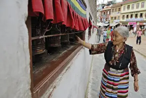 Pilgrim walking around stupa of Boudhanath and turning prayer wheel