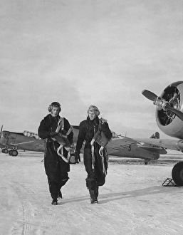 Pilots in the 1950s. Two pilots are walking past fighter aircraft a winter day