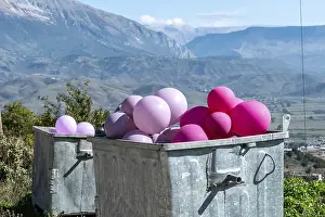 Framed Print : Pink balloons in a metal container in front of a mountain landscape of Gjirokaster Framed Print : Pink balloons in a metal container in front of a mountain landscape of Gjirokaster