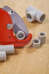 Pipe cutter and polypropylene cutted pipes on wooden boards