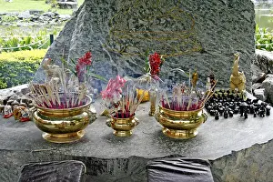 Place of worship with incense sticks at the Buddha image on a cliff