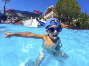 Playful child with blue sunglasses and hat pointing with finger