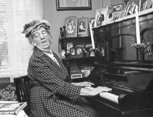 Playing the piano. An elderly lady at the piano, singing the song to accompany the music. She is actress Julia Caesar 1885-1971 at home. Sweden 1965