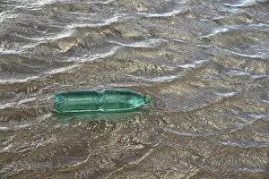 Pollution theme with a green plastic bottle floating on water surface