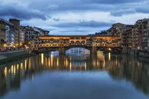 Ponte Vecchio and the buildings close by at night reflecting on the river Arno