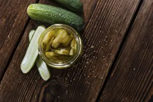 Portion of sliced and pickled Cucumbers (close-up shot) on wooden background