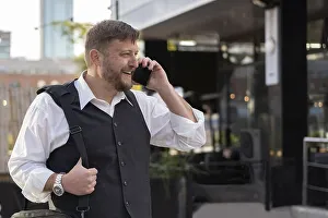 Portrait of an attractive businessman talking on the cell phone to a friend outside his office
