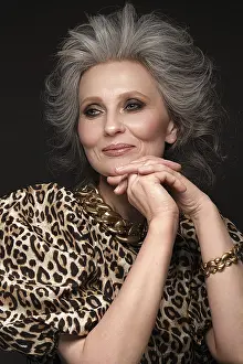 Portrait of a beautiful elderly woman in a leopard blouse with classic makeup and gray hair