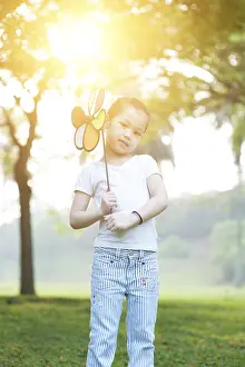 Portrait of cute Asian kid playing windmill toy outdoors