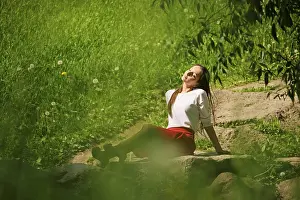Portrait of a girl in red skirt and white blouse sitting on stone on river bank