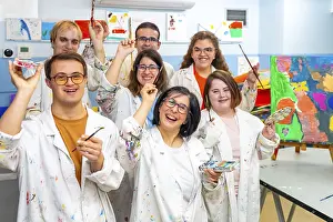 Portrait of a group of happy disabled people with dirty coats in a painting class