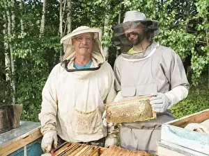 Portrait of two male beekeeper working in an apiary near beehives with bees