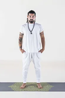 Portrait of a man dressed in white yoga clothes over white background while looking at camera