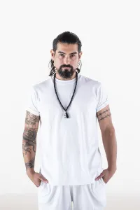 Portrait of a man dressed in white yoga clothes over white background while looking at camera
