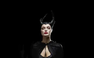 A portrait of a woman in a dark costume with horns and dramatic expression