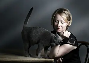 Portrait of a woman with her Russian Blue pedigree cat showing her affection