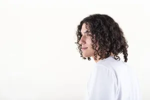 Portrait of a young man dressed in white yoga clothes over white background