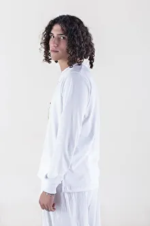 Portrait of a young man dressed in white yoga clothes over white background while looking at camera