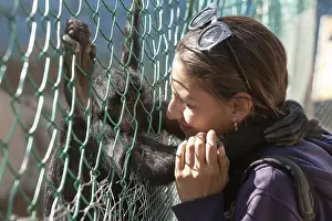 Portrait of a young woman playing and hugging spider monkey in ZOO