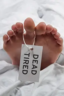 Practical joke toe tag on a tired asleep woman