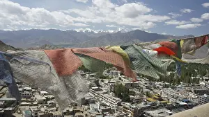 Prayer flags fly over Leh, a city with mountains and cloudy sky in the background