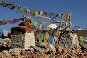 Prayer flags, mani stones and chorten of Chiu Gompa monastery in front of snow-covered Mount Kailash