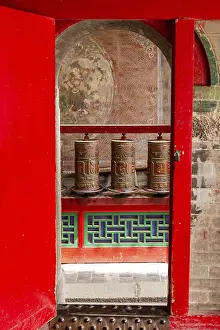 Prayer wheels behind a gate in a Tibetan temple of the Kumbum Jampaling monastery complex in Xining