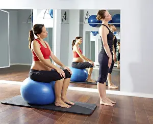 Pregnant woman pilates exercise fitball at gym with personal trainer