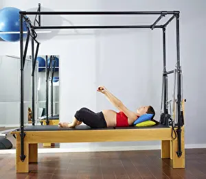 Pregnant woman pilates reformer cadillac exercise workout at gym