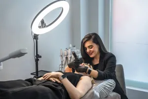 Professional beautician performing a facial treatment using a led light therapy device on a client lying on a treatment