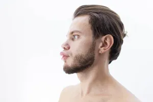 Profile view of a bearded person looking ahead against a white background