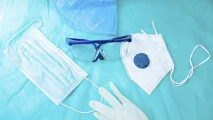 Protective gear spread on blue surface including a mask