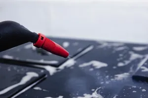 Puff from red nozzle onto a soapy stove surface
