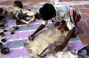 Puppet artist giving shape to the outline leather puppet making at Madurai