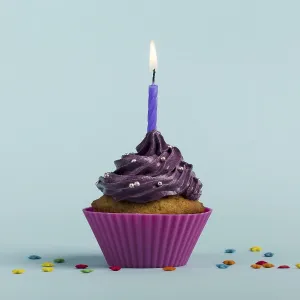 Purple burning candles decorative muffins with colorful star sprinkles against blue backdrop