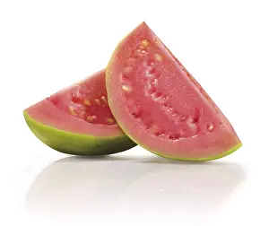 Two quarters of a sliced guava (Psidium guajava) in front of a white background