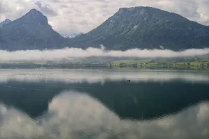Quiet lake landscape with a small boat and mountains in the background