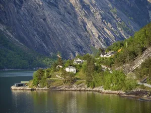A quiet lakeshore with cottages and steep mountains in the background