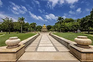 Quiet park with centrally placed Buddha statue and stone path under blue sky