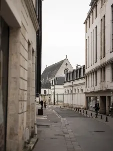A quiet street lined with historic buildings leading to a church on an overcast day in Tours