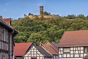 A quiet village scene with half-timbered houses and a castle on a hill