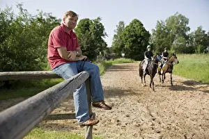 Racehorse trainer Werner Glanz observing his jockeys during training on the training track of Munich Racecourse