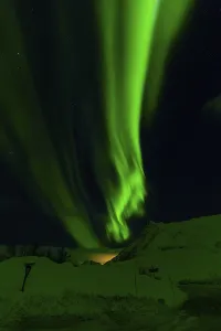 Radiant green aurora borealis streaks across a star-filled sky