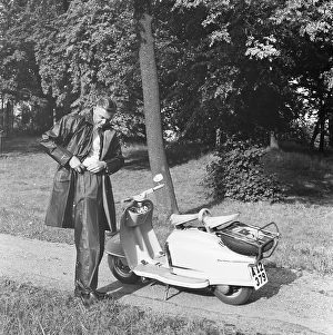 Rain in the 1950s. A young man prepares for a tour on his scooter motorcycle NSU Prima
