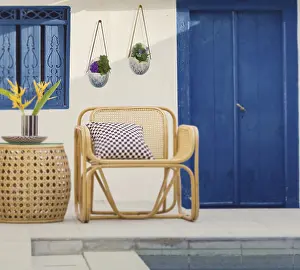 Rattan chair by a poolside with blue door and window