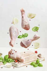 Raw chicken drumstick And spices fly over the cutting board