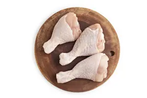 Raw chicken legs on a wooden cutting board isolated on white background